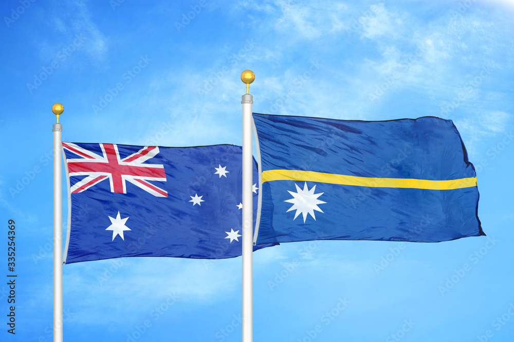 Fototapeta premium Australia and Nauru two flags on flagpoles and blue cloudy sky