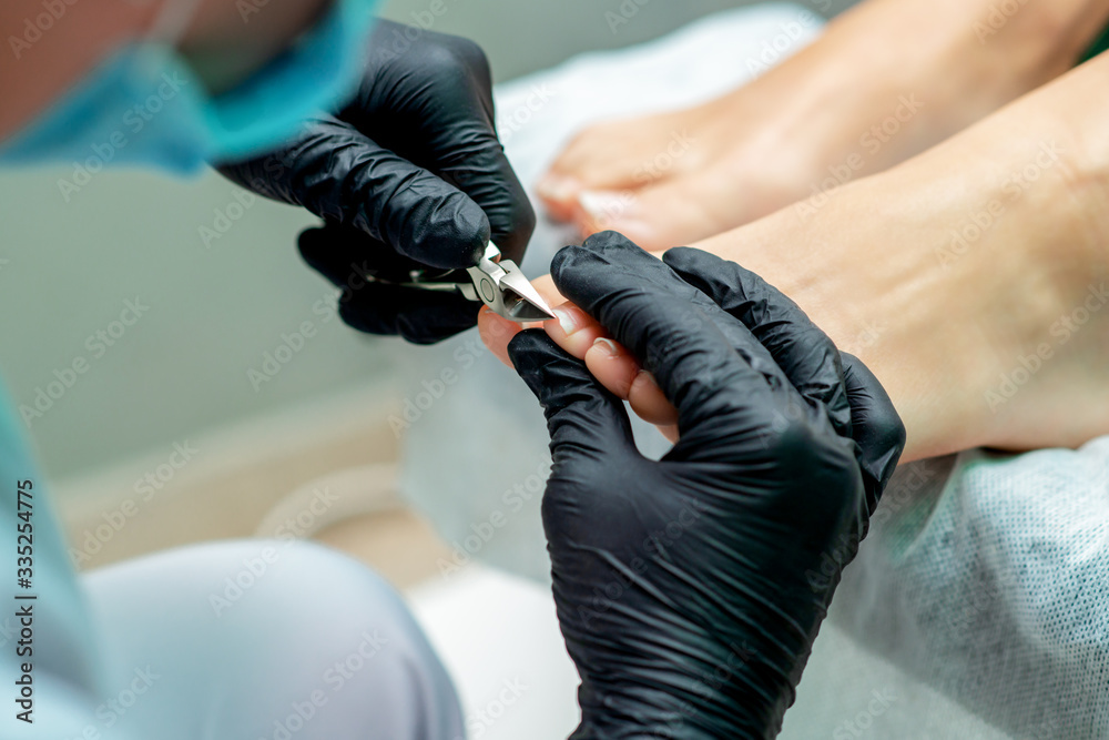 Pedicure master cuts toenails of woman during pedicure procedure. Stock