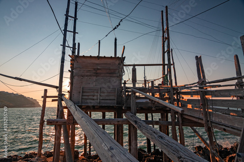 Trabucco, ancient wooden structure of the fishermen of the lower Adriatic Sea in the Gargano in Italy, in the sunset light. © serghi8