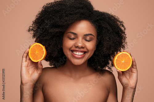 Happy black woman with ripe orange photo