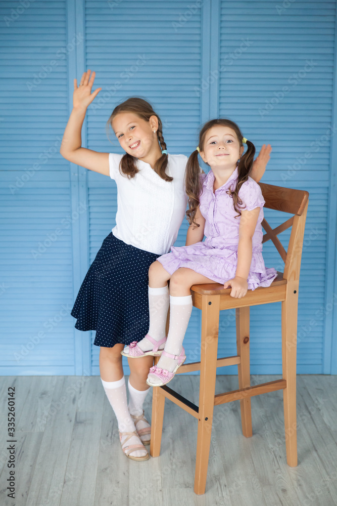 School girl in a uniform and her sister pre-school kid School girl in a uniform and her sister pre-school kid