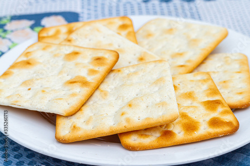 Several cream cheese crackers on a white plate on a blue tablecloth