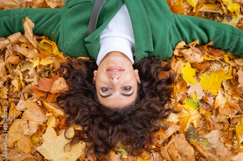 Gladsome woman lying in autumn leaves stock photo