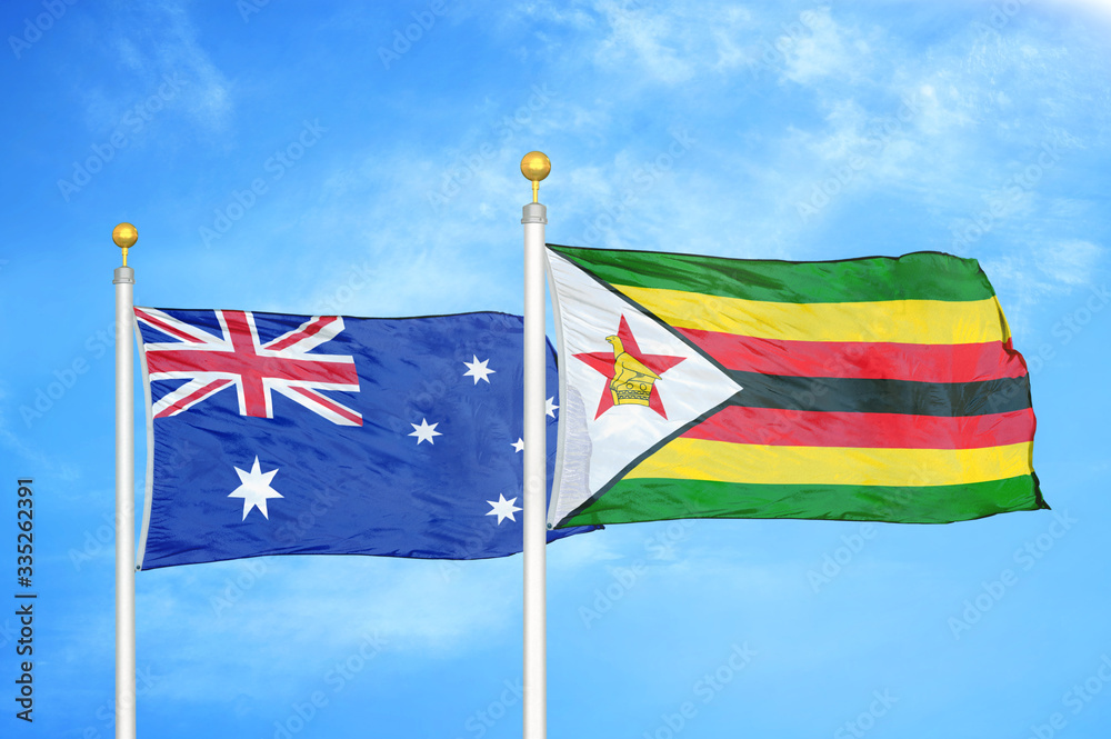 Australia and Zimbabwe two flags on flagpoles and blue cloudy sky