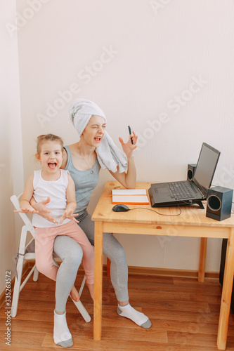Home office in quarantine, self isolation, stay home, working from home while quarantine, woman with towel on head works at home, woman works with baby, a kid makes noise.