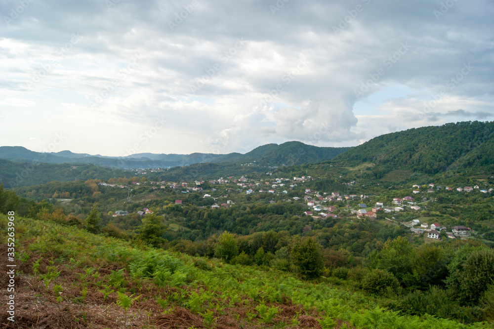 Obraz premium Mountain landscape - summer, mountains, sky and small houses in the lowlands.