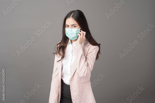 Business woman with surgical mask is using cell phone