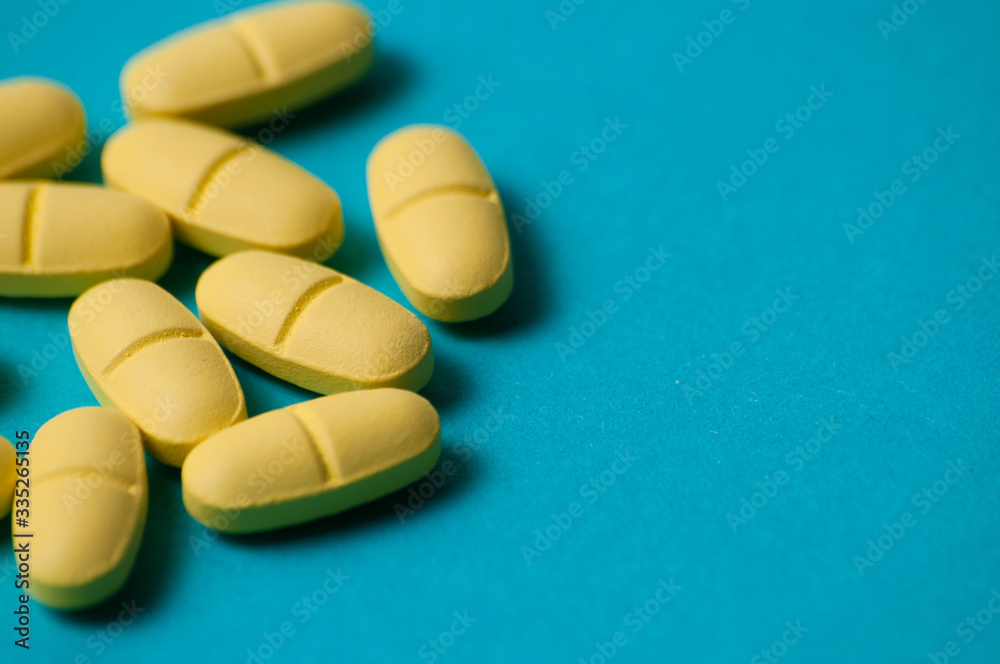 Yellow vitamins or medical pills on a blue background, macro closeup, copy space Yellow vitamins or medical pills on a blue background, macro closeup, copy space