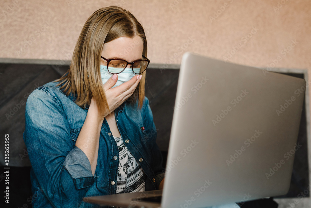 Coronavirus. Cough. Business woman working in home wearing protective mask in quarantine. Stay at home. Girl learns, using laptop computer in bedroom. Freelancer. Communication and technology concept.