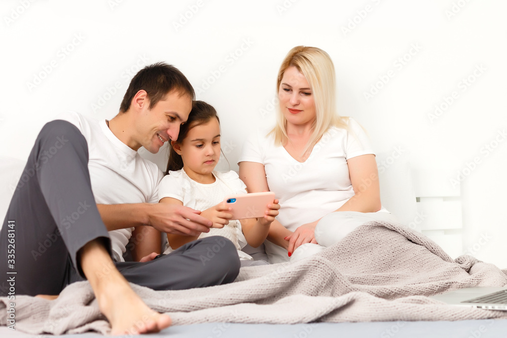 Family Lying In Bed Together Using Digital Devices Family Lying In Bed Together Using Digital Devices