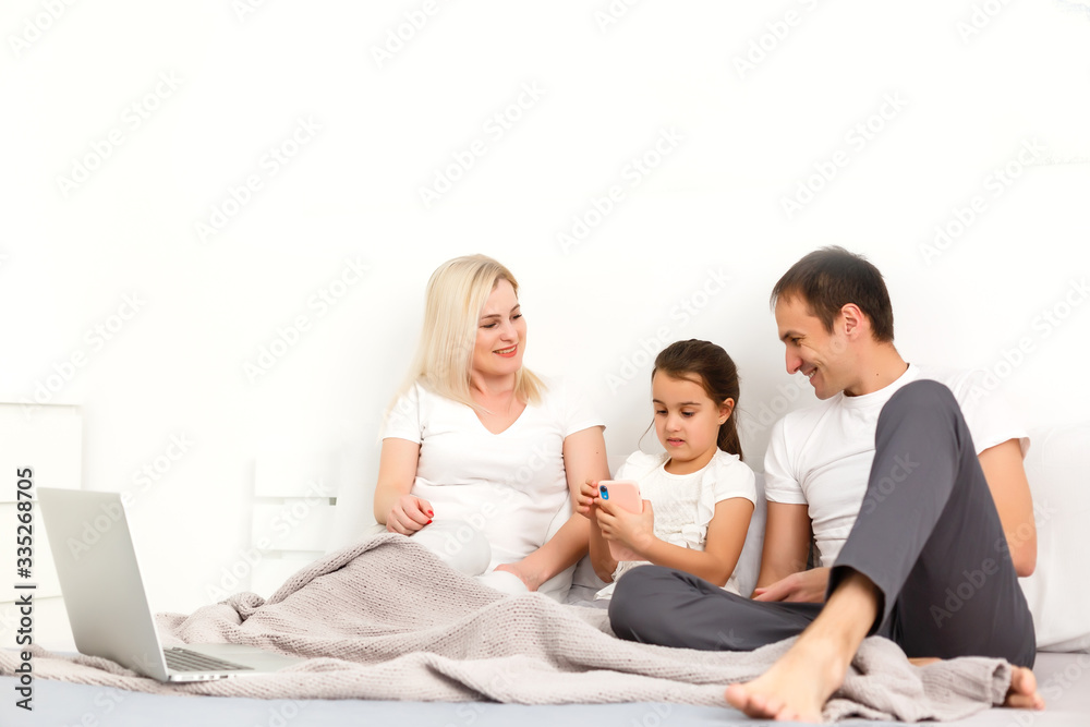 Family Lying In Bed Together Using Digital Devices Family Lying In Bed Together Using Digital Devices