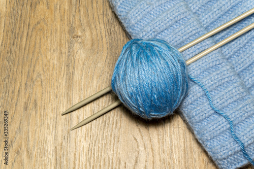 Knitting yarn and knitting needles on wooden background. Handmade hobby. 