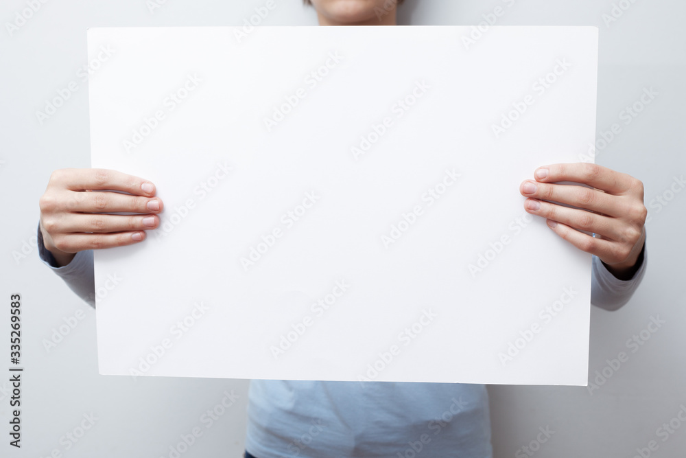 Hands hold a white sheet. Empty space for the label. Hands hold a white sheet. Empty space for the label.