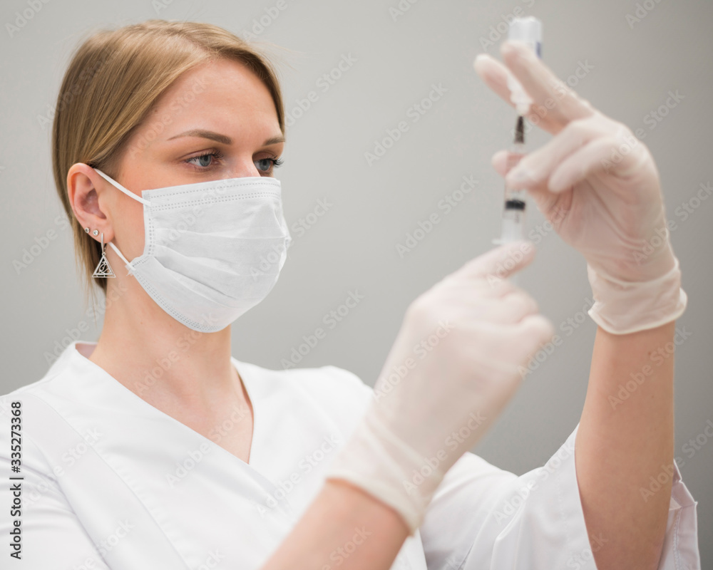 Doctor filling a syringe wearing medical face mask. Nurse woman. Doctor filling a syringe wearing medical face mask. Nurse woman.
