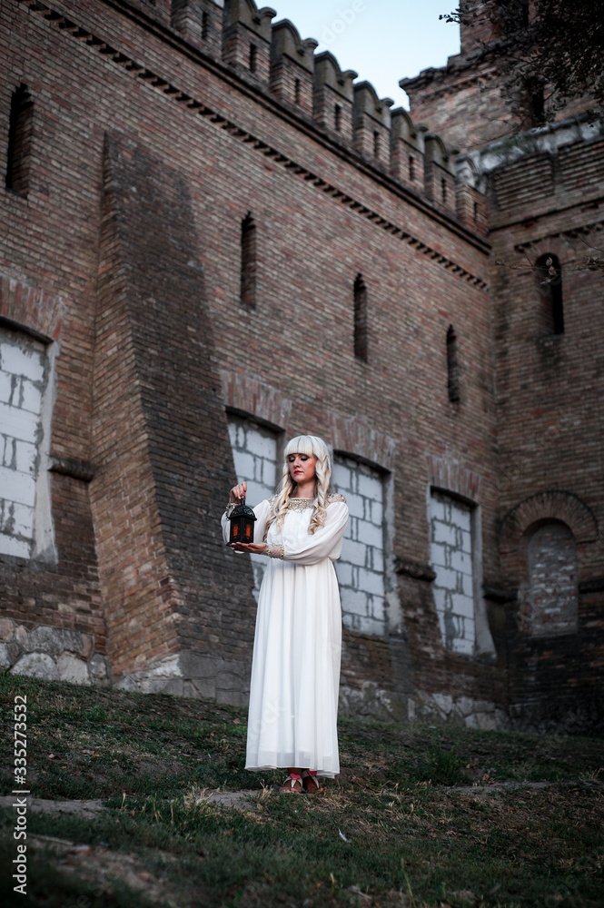 blonde girl in a white dress on nature near architectural monuments in the open air