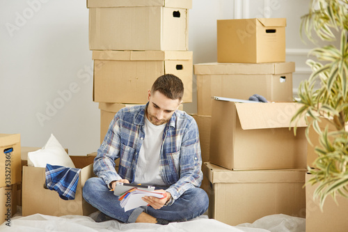 Handsome man with boxes in the new apartment after moving