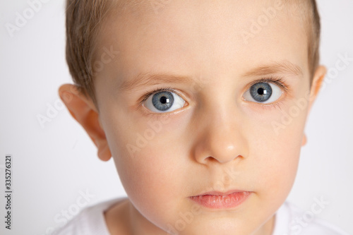 close-up portrait of a boy with big blue eyes on a white background