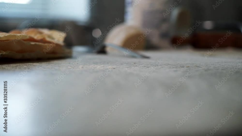 female baker sprinkles flour on the table female baker sprinkles flour on the table