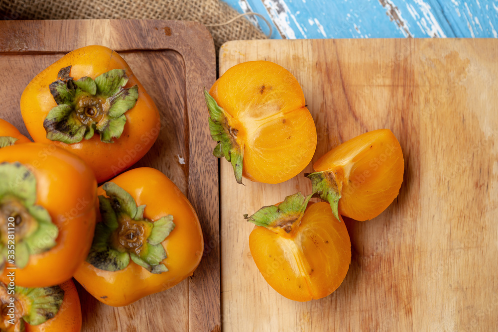 Fresh ripe persimmons on blue wooden table Fresh ripe persimmons on blue wooden table