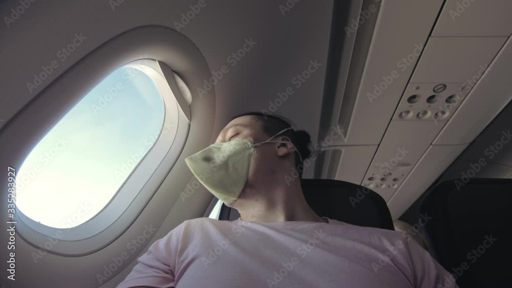 Man travel caucasian at plane with wearing protective medical mask. Male tourist at aircraft with protect respirator. Concept virus protection coronavirus pandemic sars-cov-2 covid-19 2019-ncov.