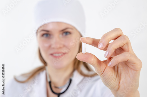 A doctor in a white coat holds out a medication.