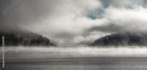 Morning fog over forest and mountain lake