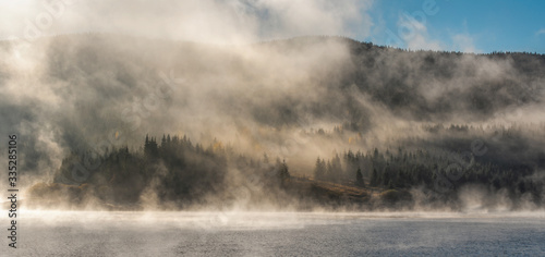 Morning fog over forest and mountain lake