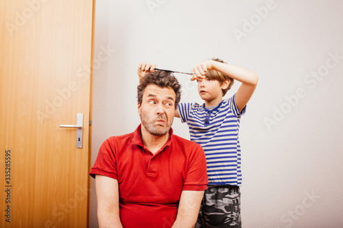 Son cutting father hair at home during 2020 pandemic crisis photo