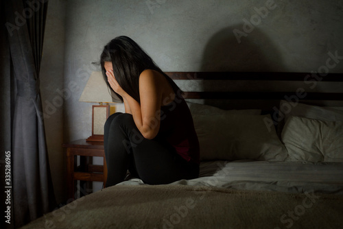 young scared and depressed Asian Korean woman suffering anxiety disorder and depression problem crying on bed in panic about covid-19 quarantine home lockdown photo