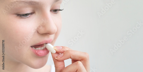 Beauty portrait of a pretty young woman holding pill on white background