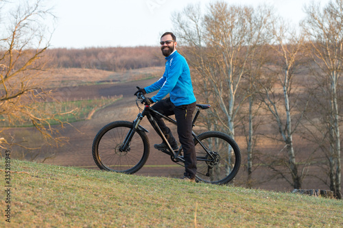 Cyclist in pants and fleece jacket on a modern carbon hardtail bike with an air suspension fork. The guy on the top of the hill rides a bike.