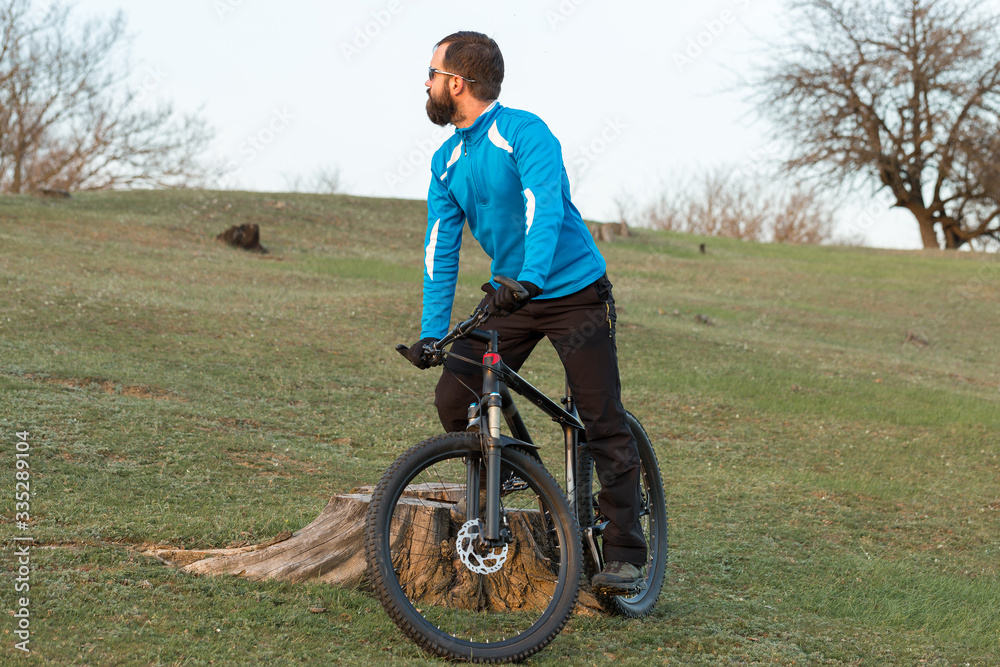 Cyclist in pants and fleece jacket on a modern carbon hardtail bike with an air suspension fork. The guy on the top of the hill rides a bike. Cyclist in pants and fleece jacket on a modern carbon hardtail bike with an air suspension fork. The guy on the top of the hill rides a bike.