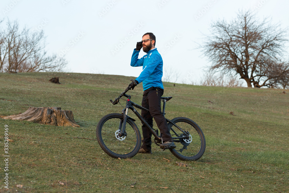Cyclist in pants and fleece jacket on a modern carbon hardtail bike with an air suspension fork. The guy on the top of the hill rides a bike. Cyclist in pants and fleece jacket on a modern carbon hardtail bike with an air suspension fork. The guy on the top of the hill rides a bike.
