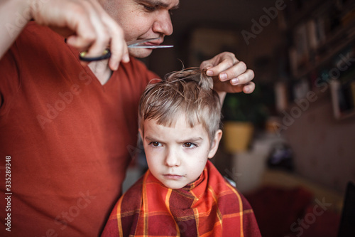 Middle aged father cutting hair to his little son by himself at home, life during lockdown