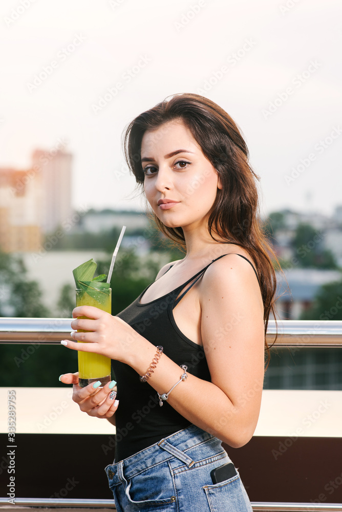 Pretty girl with yellow cocktail relaxing on the balcony with beautiful view Pretty girl with yellow cocktail relaxing on the balcony with beautiful view