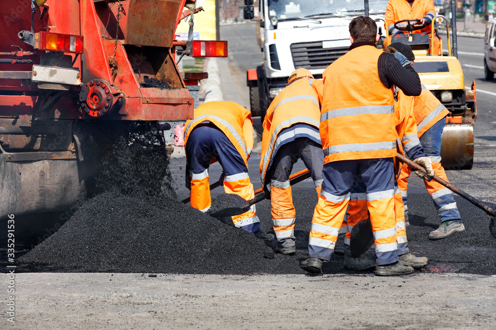 The working team scatters a part of the asphalt with shovels to repair a section of the road. The working team scatters a part of the asphalt with shovels to repair a section of the road.