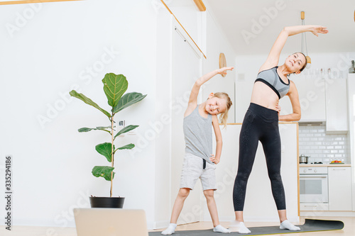 Smiling mother and son doing side bends exercise, keeping fit