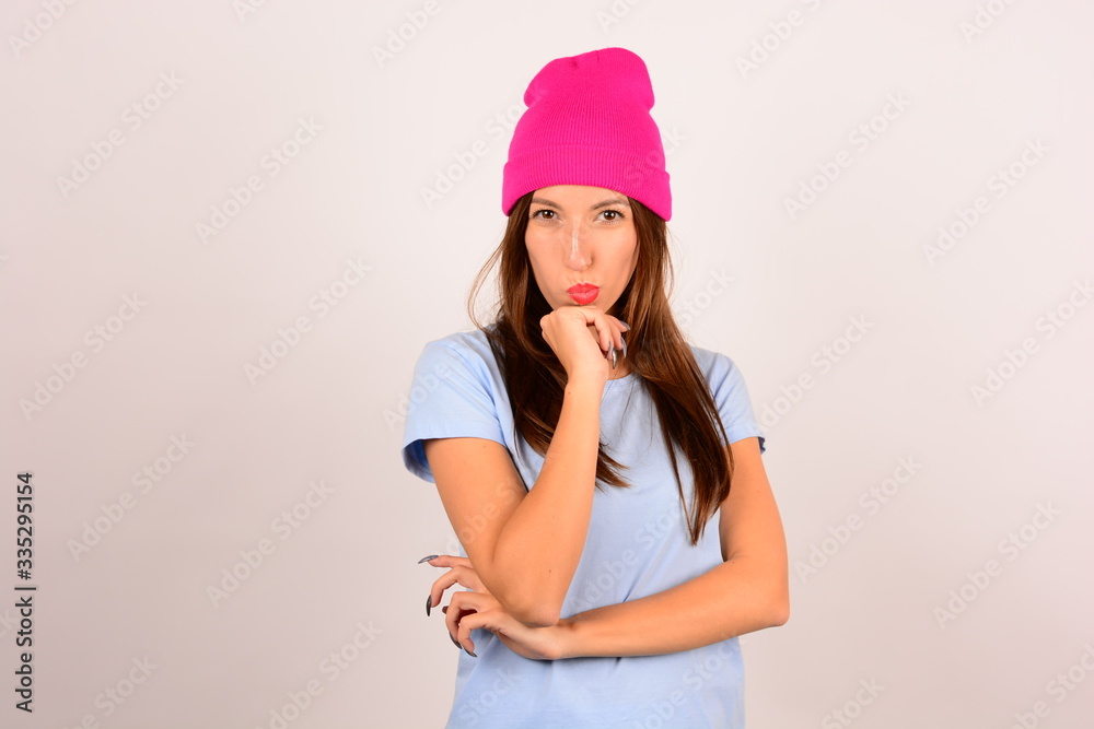 woman in pink hat in blue t-shirt looking at camera portrait studio