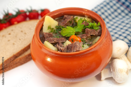 Roast in a pot with beef meat and potatoes on the table