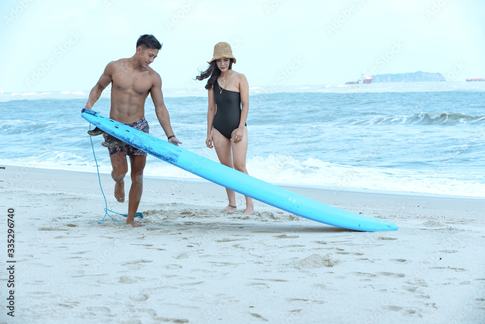 Obraz premium Asian surfer teacher man teach practice woman student during private surf class lesson.