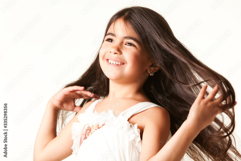 Smiling girl buried hands in her long brown hair, dressed in white blouse, isolated on white background and looking away Smiling girl buried hands in her long brown hair, dressed in white blouse, isolated on white background and looking away