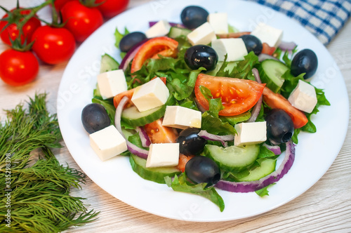 Greek salad with tomatoes, cucumbers and feta cheese with olives on the table