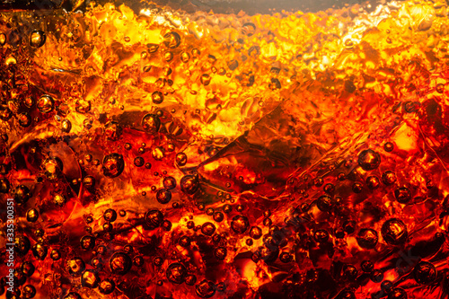 Close up view of the ice cubes in dark cola background. Texture of cooling sweet summer's drink with foam and macro bubbles on the glass wall. Fizzing or floating up to top of surface