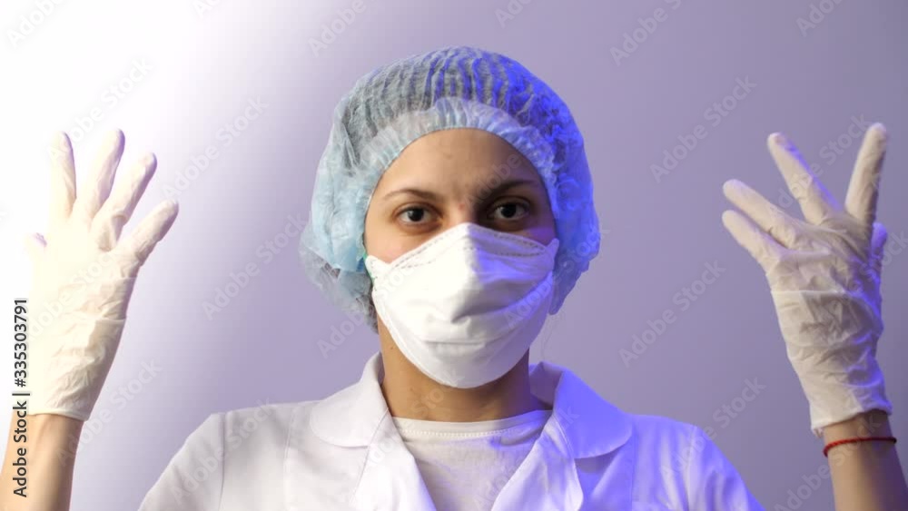 Portrait of a female doctor in medical mask, white lab coat and a protective hat for hair, and rubber protective gloves. Coronavirus or covid-19. Portrait of a female doctor in medical mask, white lab coat and a protective hat for hair, and rubber protective gloves. Coronavirus or covid-19.