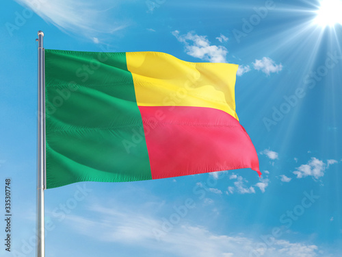 Benin national flag waving in the wind against deep blue sky. High quality fabric. International relations concept.