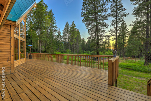 Luxury summer mountain cabin home with large green lawn and pine trees.