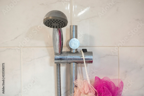 Dirty chrome shower rod with limescale that should be cleaned. Calcified shower due to hard water. Calcium mineral buildup.
