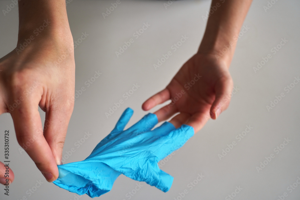 Woman hands remove a wearing blue disposable latex glove, taking off a  rubber glove for professional medical safety and hygiene protection from  Coronavirus disease COVID-19 and surgery and medical Stock Photo