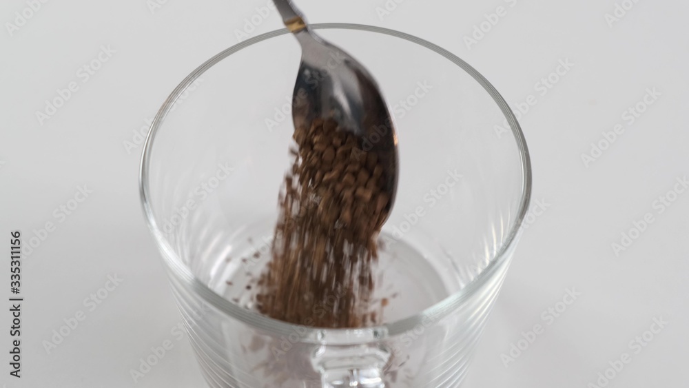 Spoon with instant coffee puor in a white mug on a black background. Slow motion. Spoon with instant coffee puor in a white mug on a black background. Slow motion.