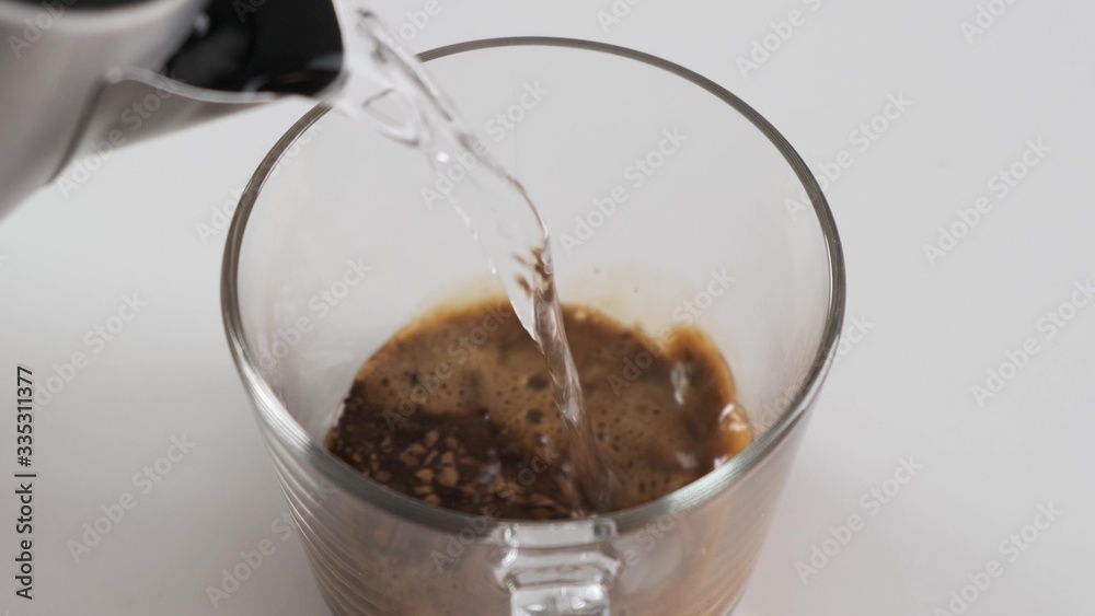 Making instant black coffee in glass cup. Pour hot water. Slow motion. Making instant black coffee in glass cup. Pour hot water. Slow motion.